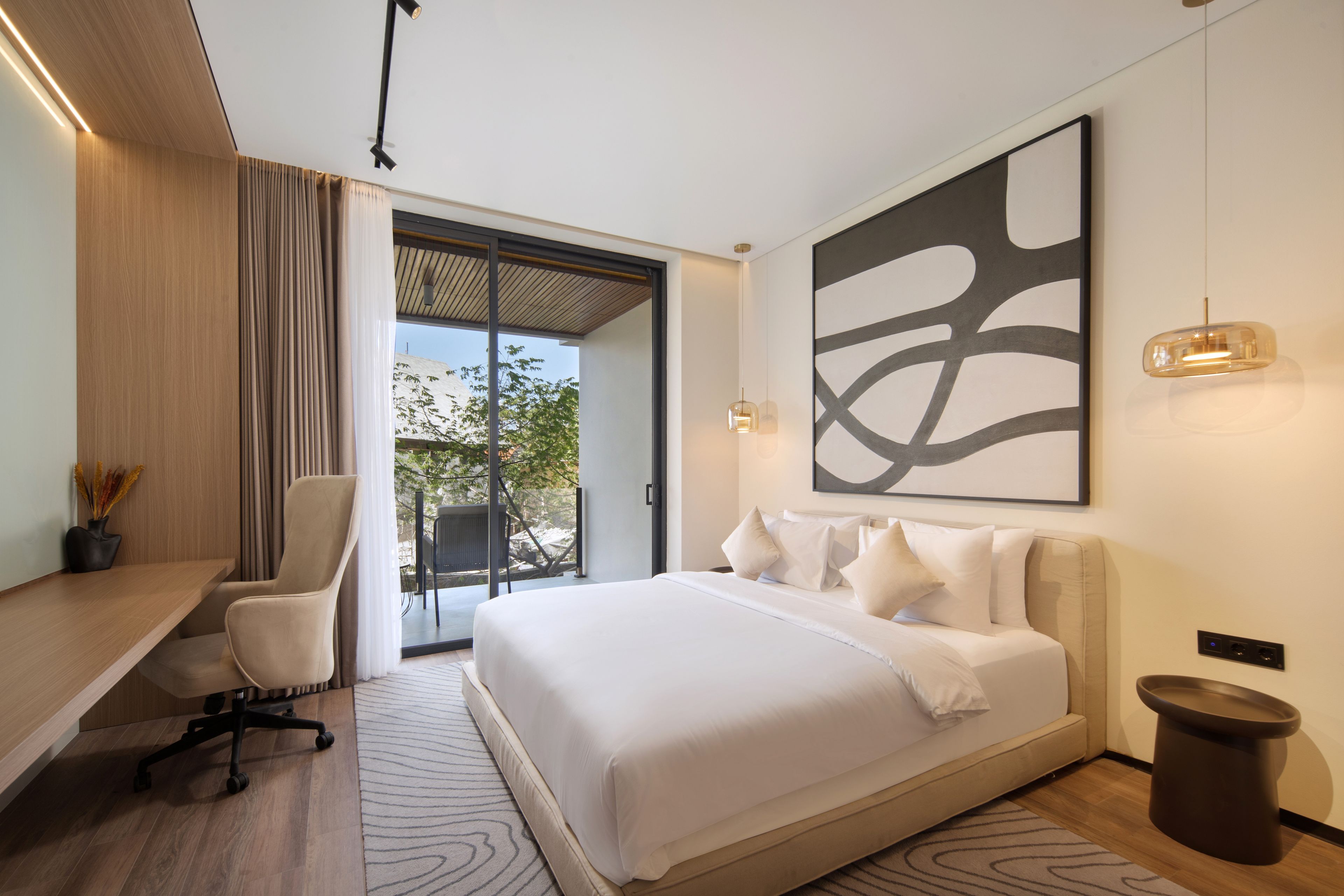 A modern bedroom with a bed, desk, chair, and artwork.