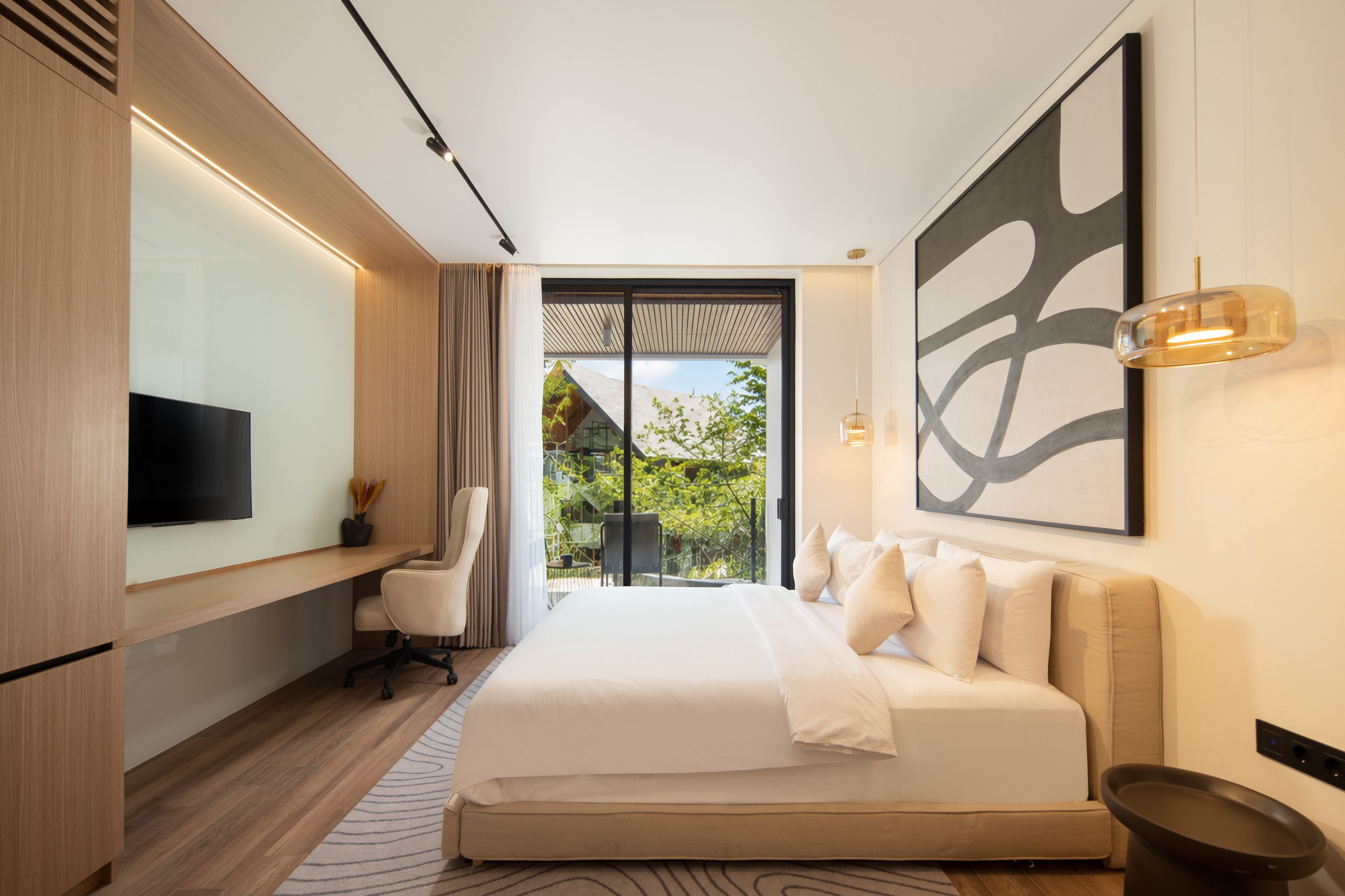 A modern bedroom with a large bed, a desk, a chair, and a TV.