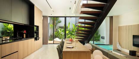 A modern kitchen with a dining area, a staircase, and a view of the outdoors.