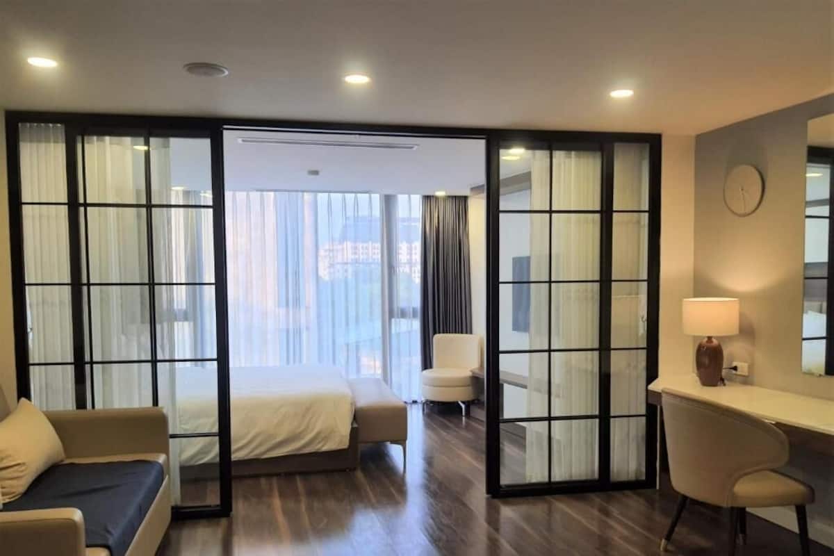 Habitación de hotel moderna con una cama, un escritorio y una silla. Posee un puerta corrediza que da a un balcón con cortinas.