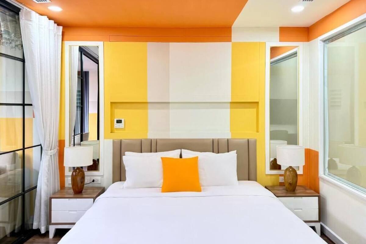 Una habitación de hotel con cama, mesitas de noche y un ventanal grande.