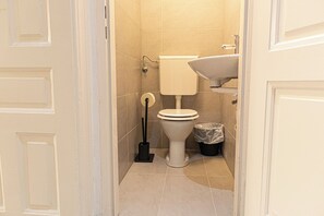 A small, clean bathroom with a toilet, sink, and trash bin. - Affordable 2BR Apt Long Stay Karlsplatz (Vienna)