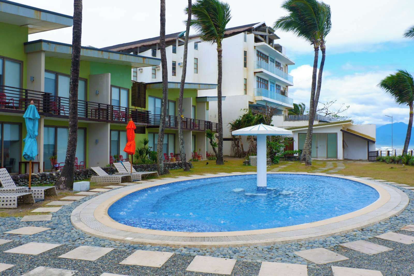 Um hotel com piscina, área de estar ao ar livre e palmeiras.