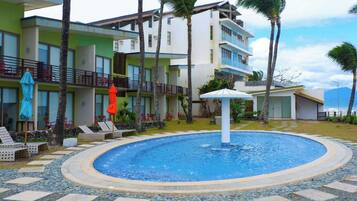 Um hotel com piscina, área de estar ao ar livre e palmeiras.