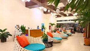A reception area with a wooden desk, a receptionist, and seating with patterned cushions.