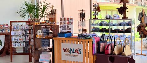 Una tienda con un letrero de madera que dice 'YANAS WOVEN TEXTILE', exhibiendo bolsas y textiles tejidos.