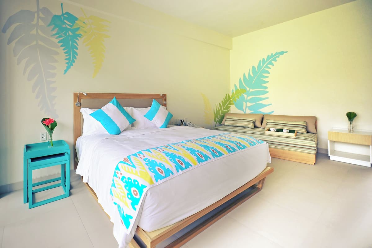 Un dormitorio con cama, mesita de noche y una pared decorada con motivos de hojas.