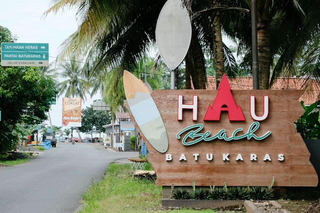 A wooden sign with "HAU Beach Batukaras" and a surfboard graphic.