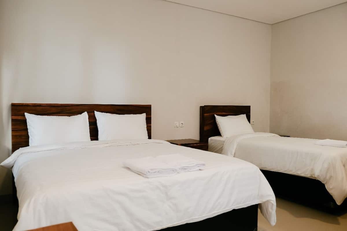Ett hotellrum med två sängar, var och en med trägavlar och vita sängkläder.