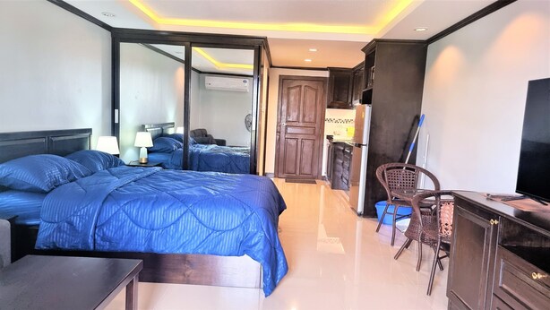 Een hotelkamer met een groot bed, een bureau, een stoel, een televisie en een kledingkast.