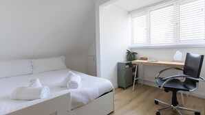 A bedroom with a bed, a desk, and a chair.