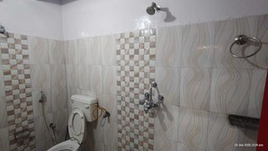 A bathroom with a toilet, shower, and a towel rack. - Radha Krishna Home (Varanasi)