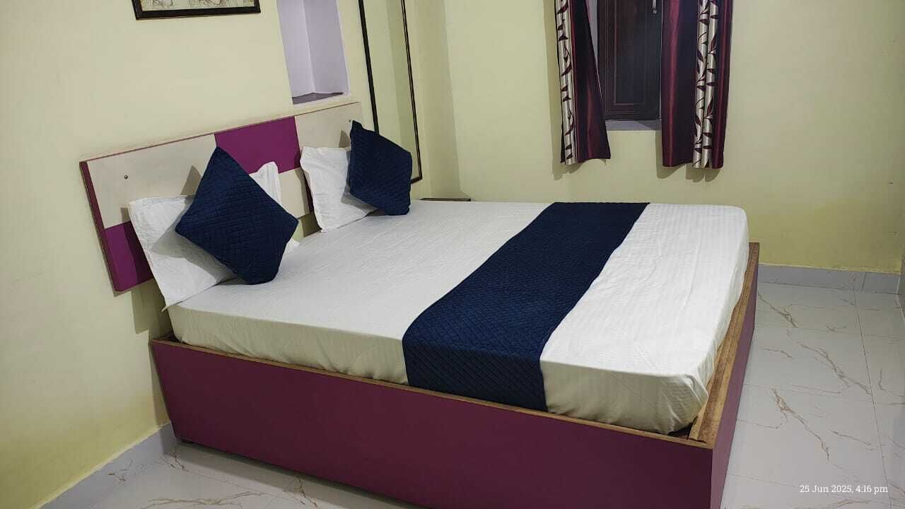 Una cama bien hecha con colcha blanca y azul, un cabecero de madera y dos almohadas.
