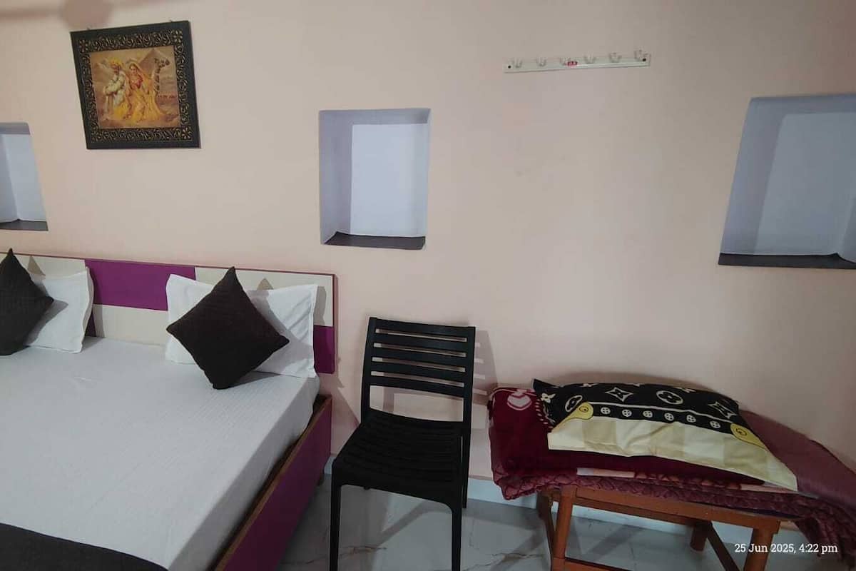 Une pièce comprenant un lit, une chaise et une petite table. Deux appliques murales et un tableau encadré sont fixés au mur, au-dessus du lit.