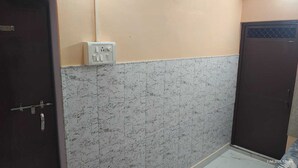 A room with a marble-patterned wall, a door with a metal handle, and a wall socket. - Radha Krishna Home (Varanasi)