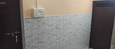 A room with a marble-patterned wall, a door with a metal handle, and a wall socket.