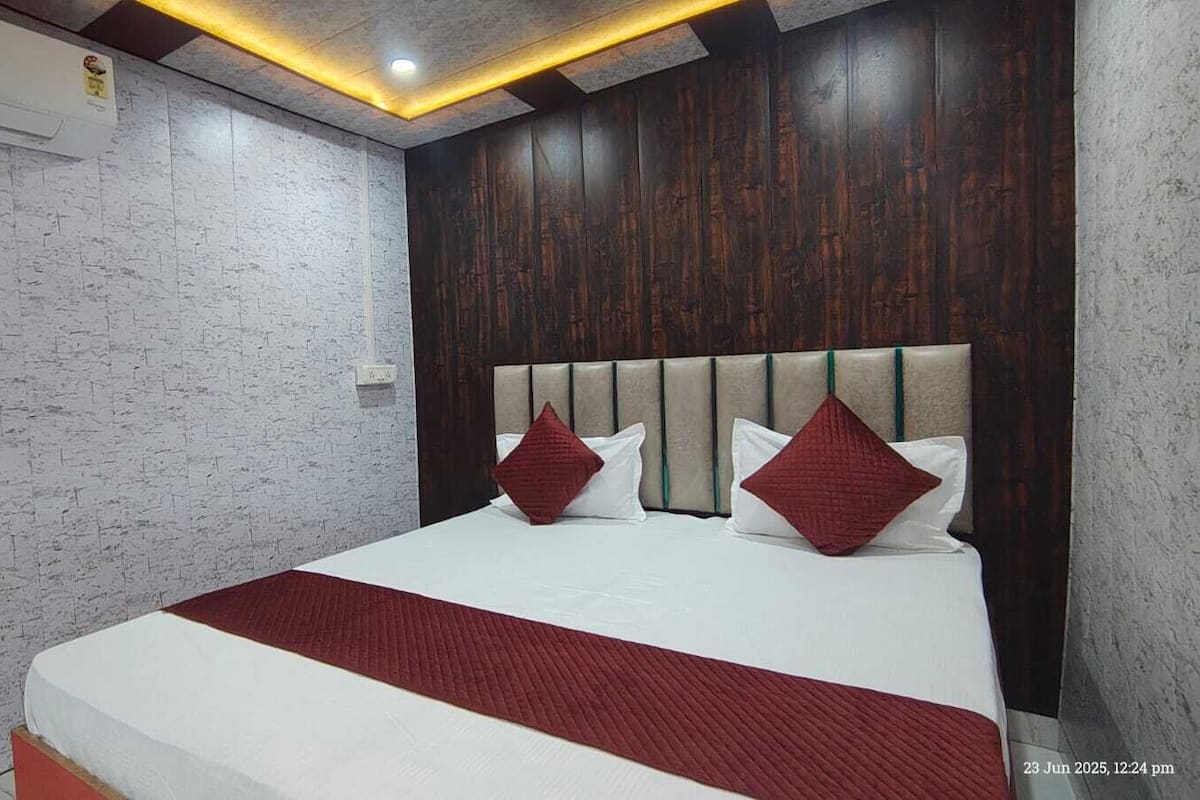 Une chambre d’hôtel moderne avec un grand lit, une tête de lit en bois et un mur blanc à la texture intéressante.