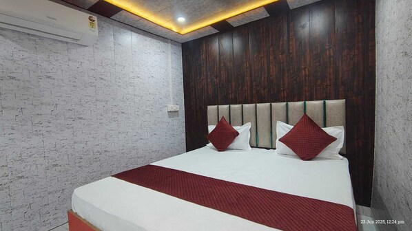 Une chambre d’hôtel moderne avec un grand lit, une tête de lit en bois et un mur blanc à la texture intéressante.