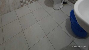 A bathroom with a toilet, bidet, and shower. The walls are tiled with a checkered pattern. - Radha Krishna Home (Varanasi)