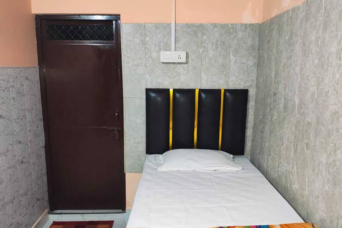 Une petite pièce, bien rangée, avec un lit, une armoire et un luminaire fixé au mur.