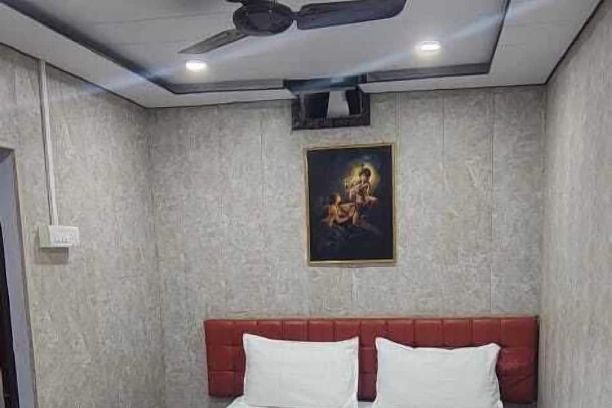 Une chambre à coucher avec un lit, un ventilateur de plafond et un luminaire fixé au mur.