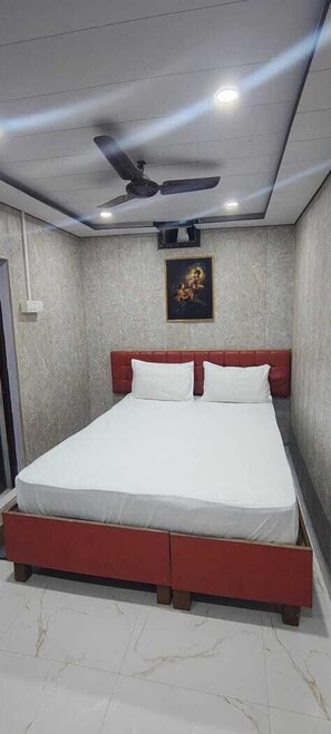 Une chambre à coucher avec un lit, un ventilateur de plafond et un luminaire fixé au mur.