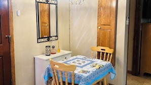 A dining area with a table, chairs, a chandelier, a mirror, and wooden cabinets. - Soothing cottage in the heart of Silicon Valley. (Santa Clara)