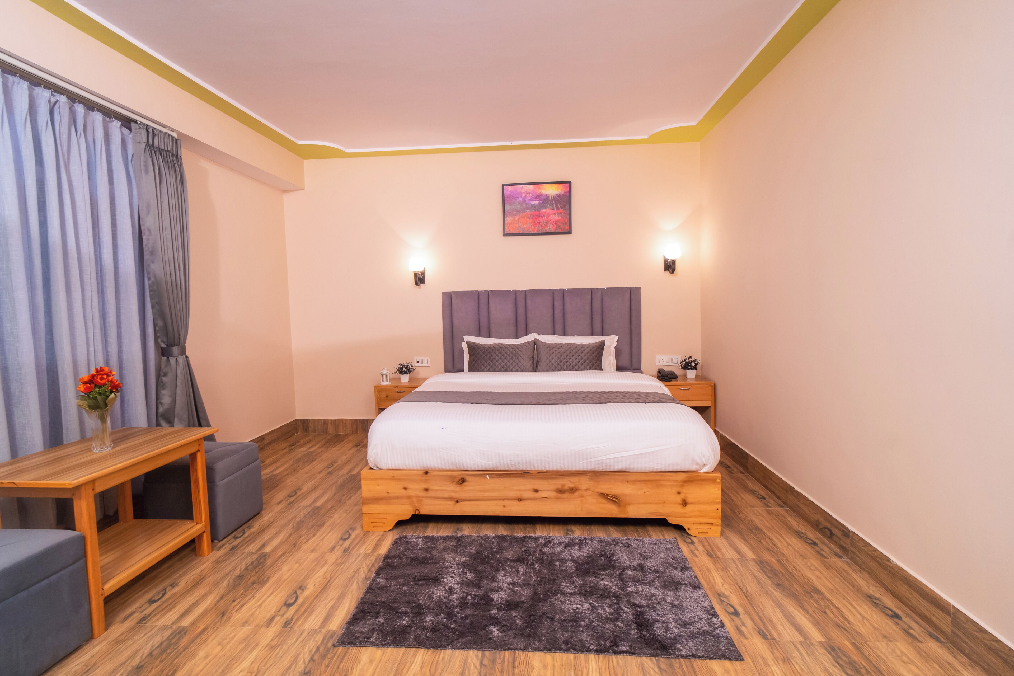 Un dormitorio con una cama de madera, una mesita, un banco y una alfombra.