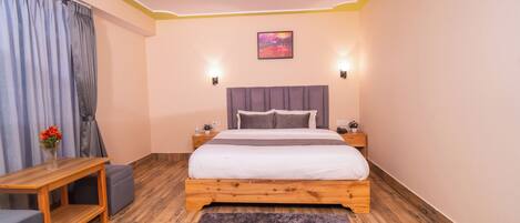 Un dormitorio con una cama de madera, una mesita, un banco y una alfombra.