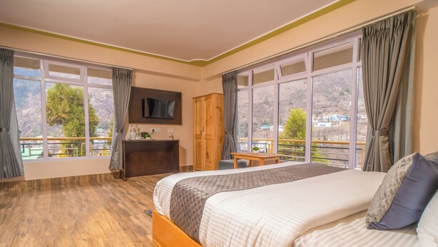 Une chambre d’hôtel avec un grand lit, une armoire en bois, un bureau et une télévision.