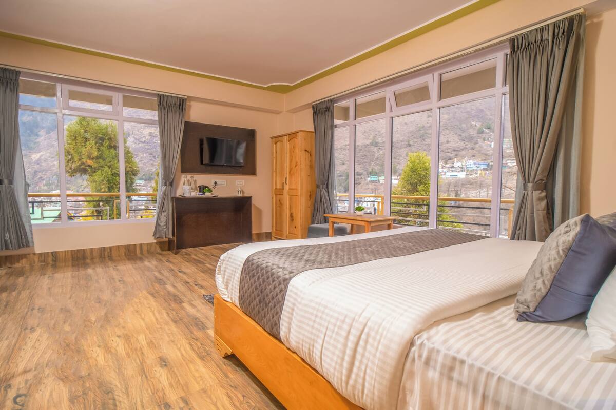 Una habitación de hotel con una cama grande, un armario de madera, un escritorio y un televisor.