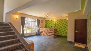 Un espace d’accueil avec un bureau en bois, une horloge et un mur décoré de motifs.