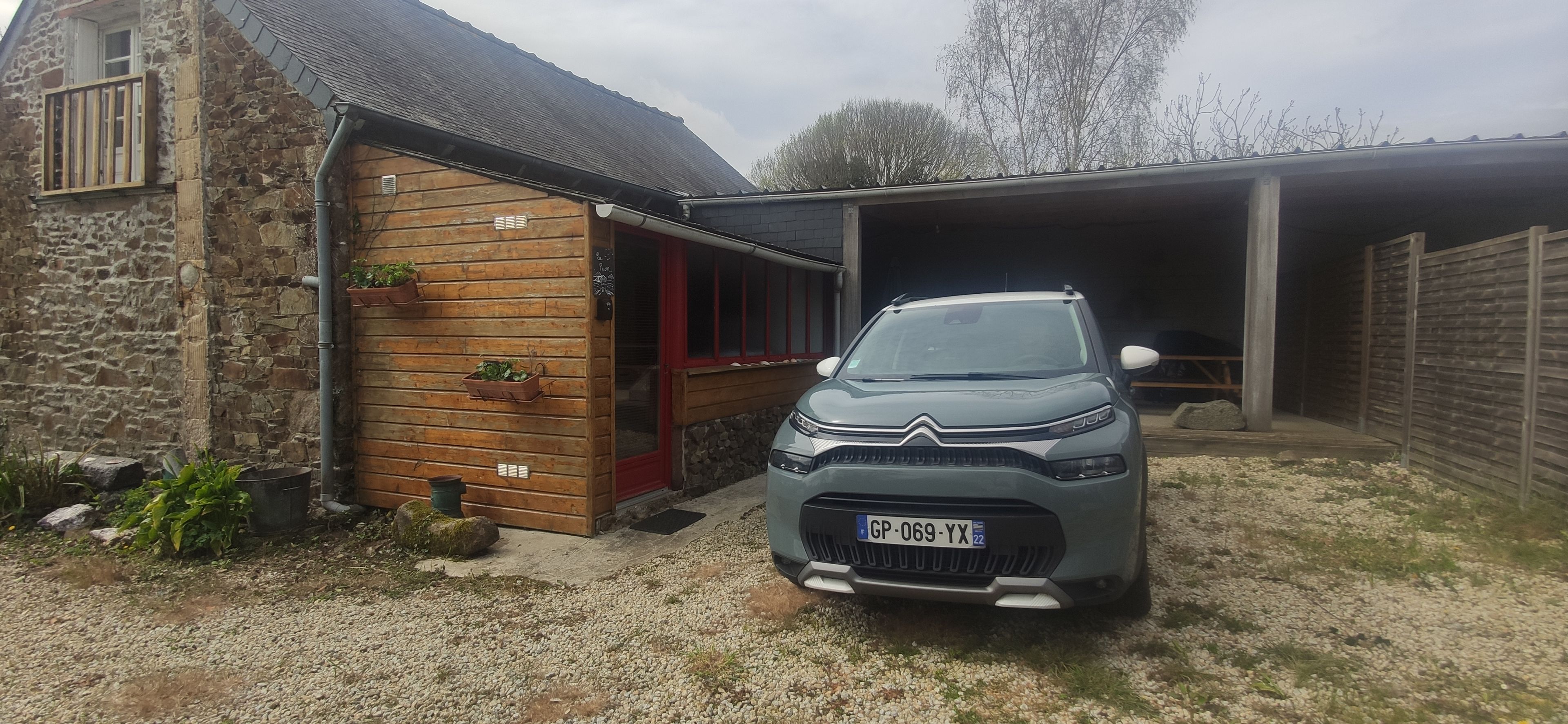 Ett fordon parkerat framför en byggnad med fasad av sten, en trädörr och ett garage.
