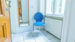 A room with a blue chair, a mirror, a radiator, and a window with a view of trees. - Simple 2BR Apt near Belvedere Palace (Vienna)