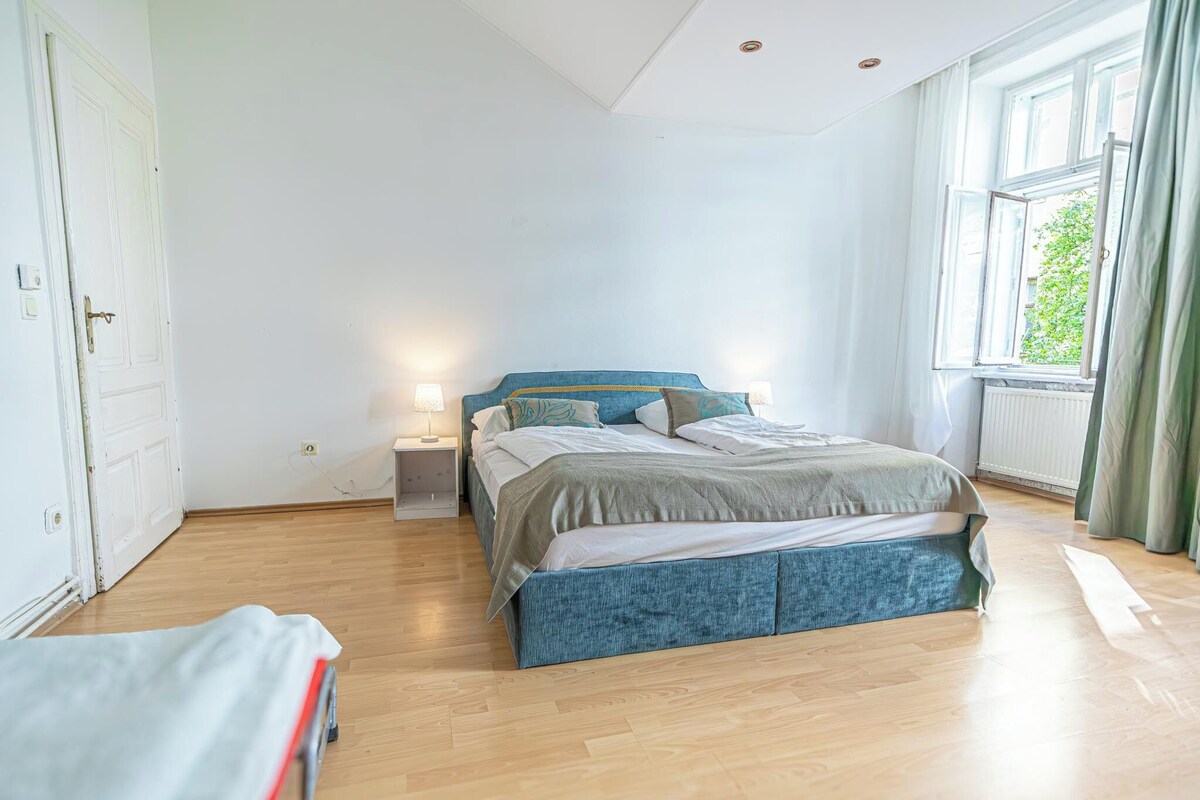 A bedroom with a bed, bedside tables, a window, and a door.