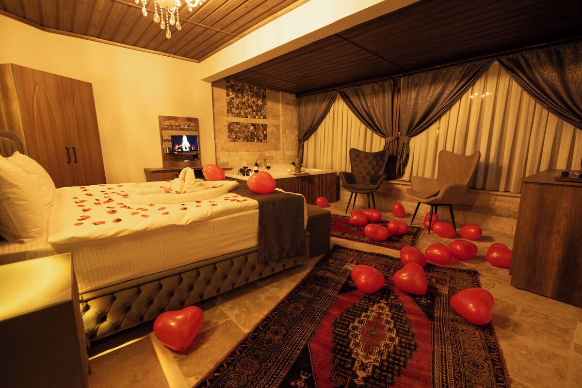 A bedroom with a bed, a desk, a chair, and a TV.
