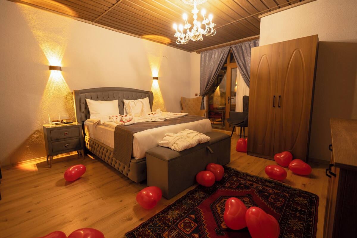A bedroom with a bed, bedside tables, a wardrobe, and a chandelier.