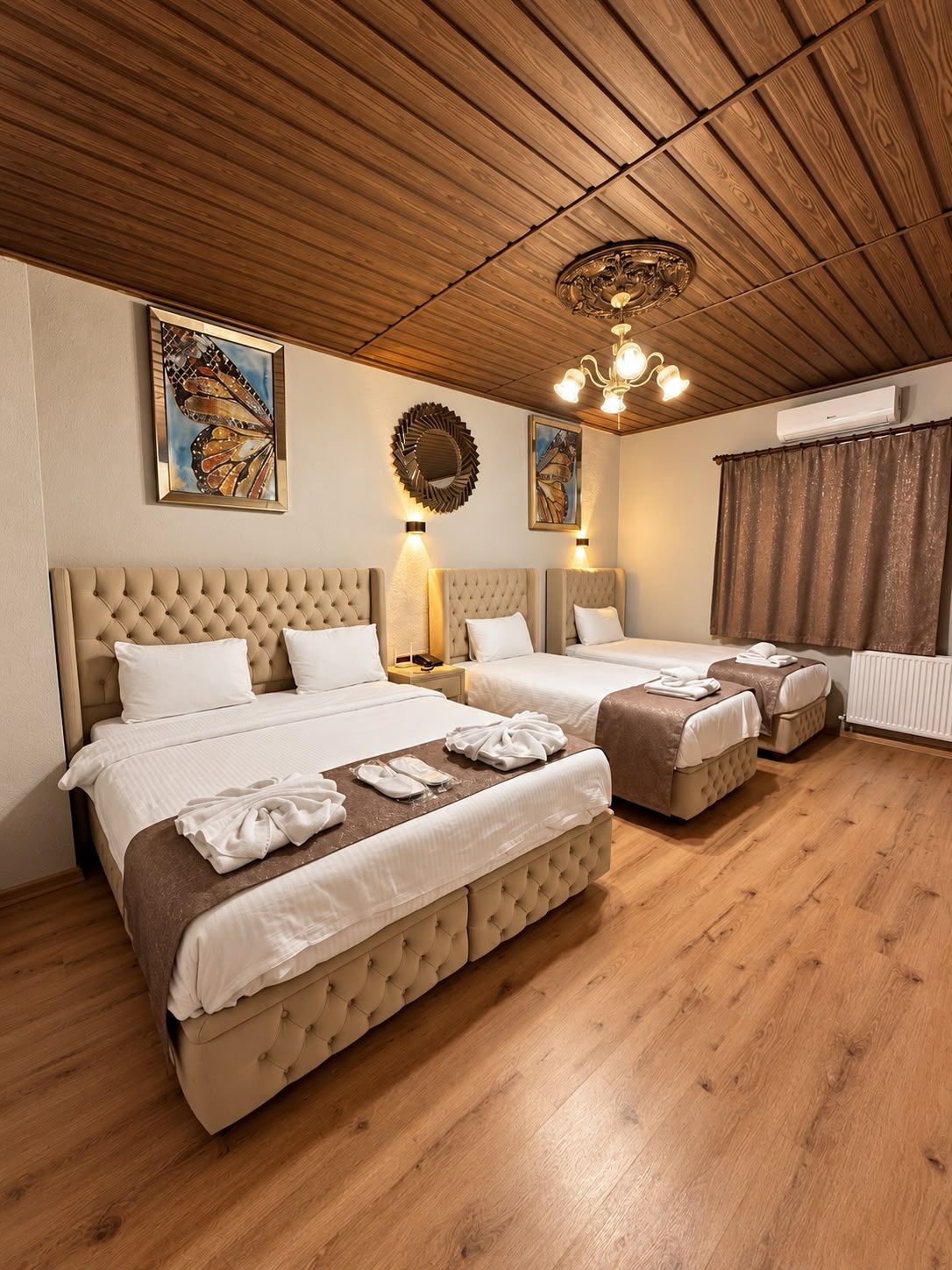 Ein Hotelzimmer mit zwei Betten, einer Holzbalkendecke und Kunstwerken an den Wänden.