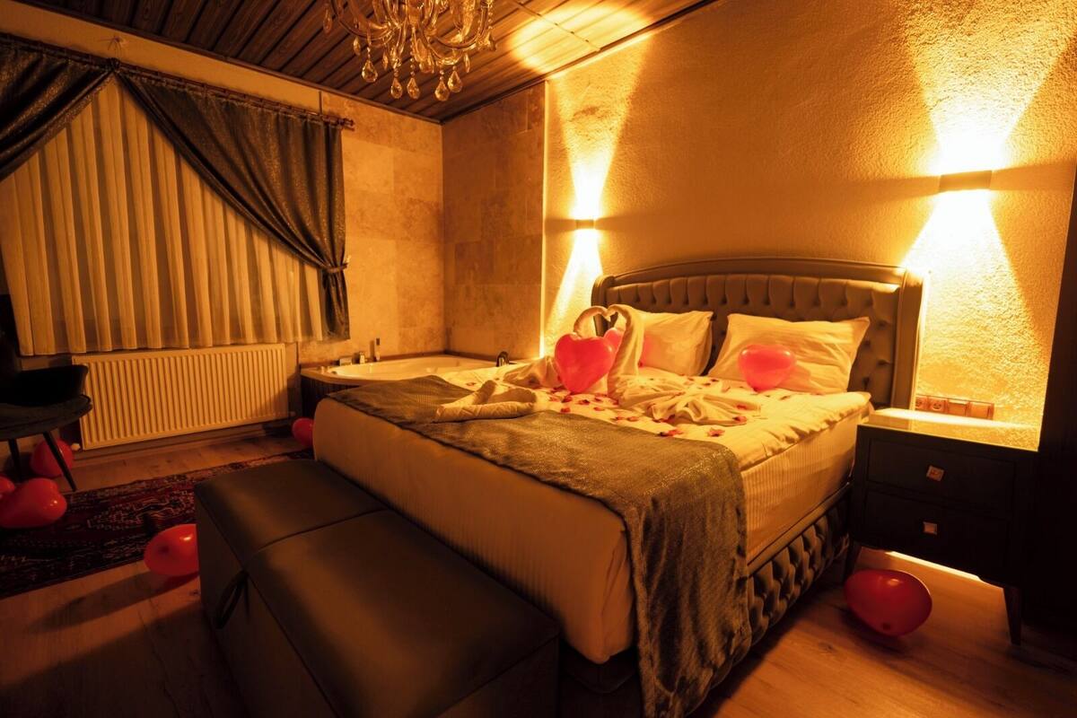 A cozy bedroom with a large bed, bedside lamps, a radiator, and a chandelier.