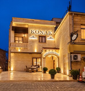 The exterior of the Konak Stone Hotel with a well-lit entrance, outdoor seating area, and potted plants. - Konak Stone House (Urgup)