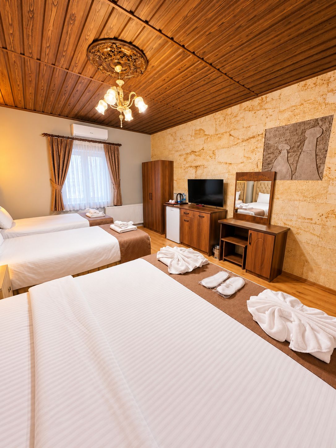 A hotel room with two beds, a television, a wardrobe, and a bathroom.