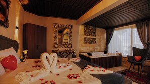 A hotel room with a bed, a bathtub, a chair, and a mirror. - Konak Stone House (Urgup)