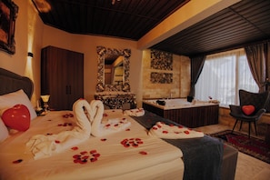 A hotel room with a bed, a bathtub, a chair, and a mirror. - Konak Stone House (Urgup)