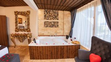A luxurious bathroom with a large bathtub, a mirror, and a console table.