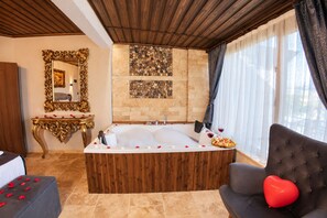 A luxurious bathroom with a large bathtub, a mirror, and a console table. - Konak Stone House (Urgup)