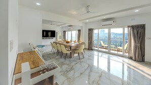 Une salle à manger spacieuse avec un sol en marbre, une table en bois et des chaises modernes. Un balcon offre une vue sur la ville.