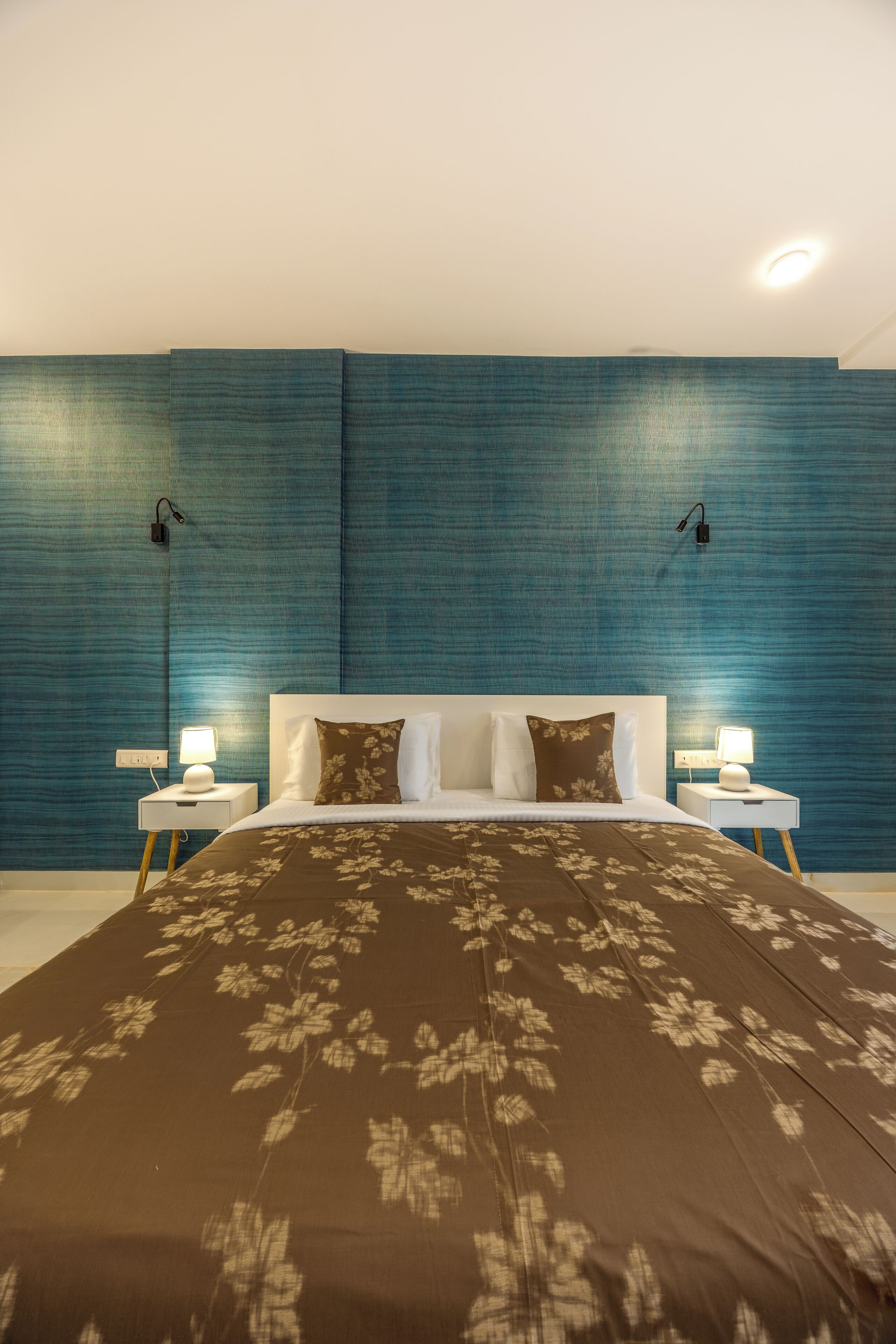 Ein Schlafzimmer mit einem großen Bett, zwei Nachttischen und einer blauen Wand mit Struktur.