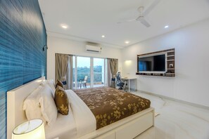 Habitación de hotel moderna con una cama grande, un escritorio y un televisor montado en la pared.