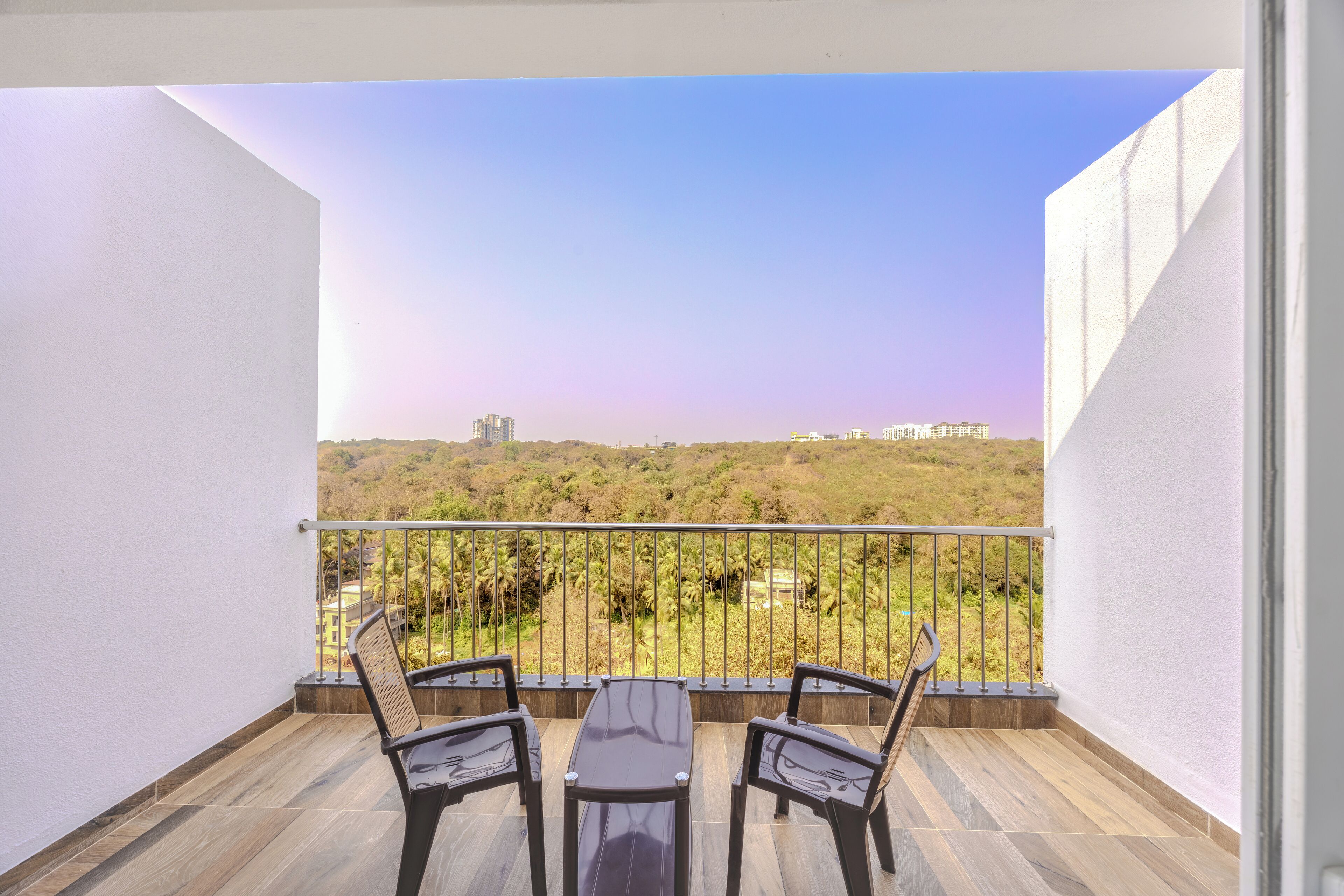 Uma varanda com vista para uma paisagem verde e edifícios ao longe.