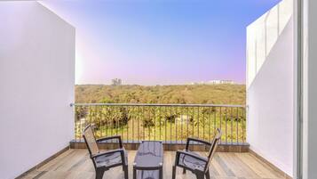 Uma varanda com vista para uma paisagem verde e edifícios ao longe.